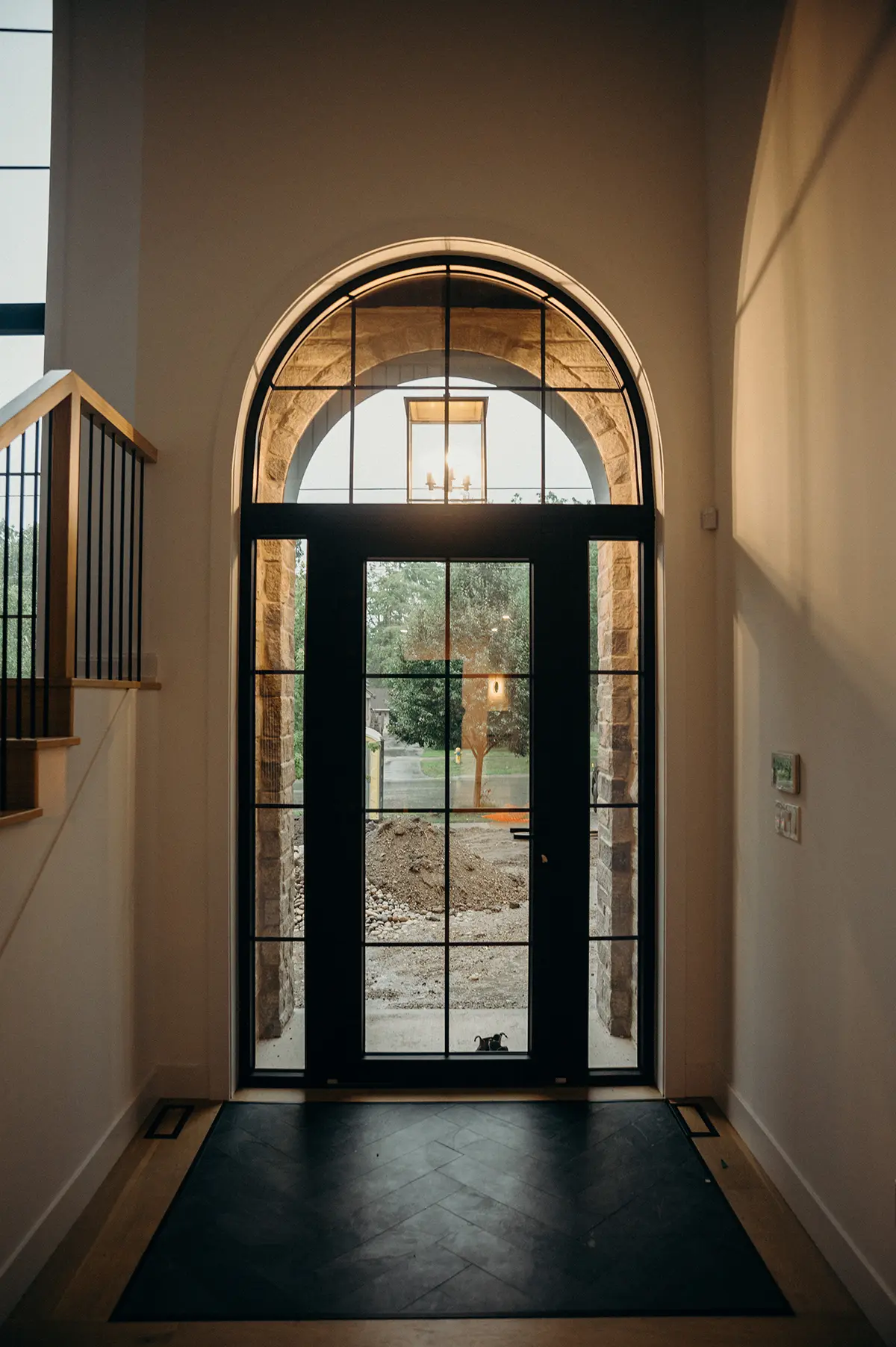 Custom home remodel by Woodfield Design + Build featuring arched entryway, stone surround, and modern front door